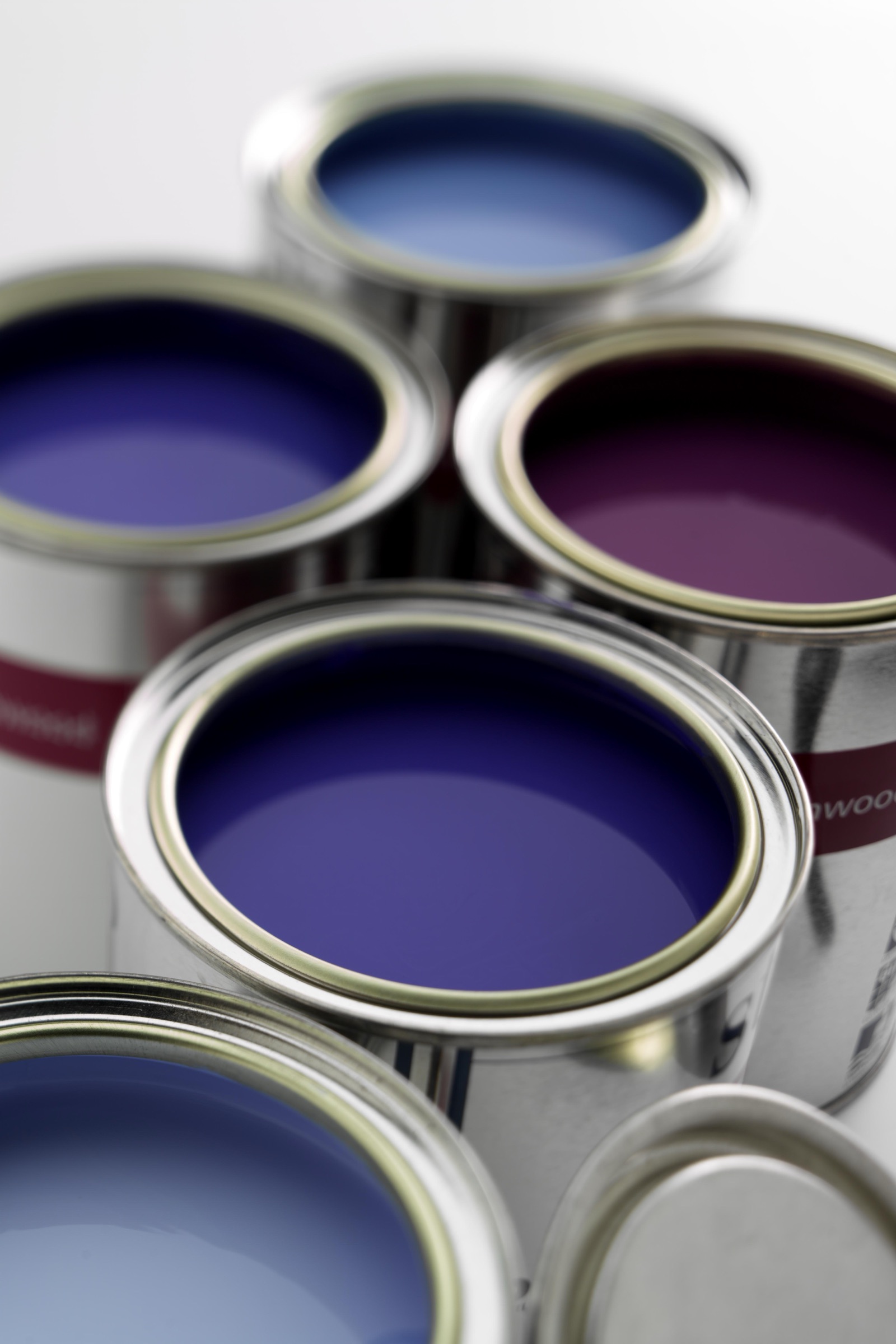 Open tins of ultramarine blue, violet and pink paint