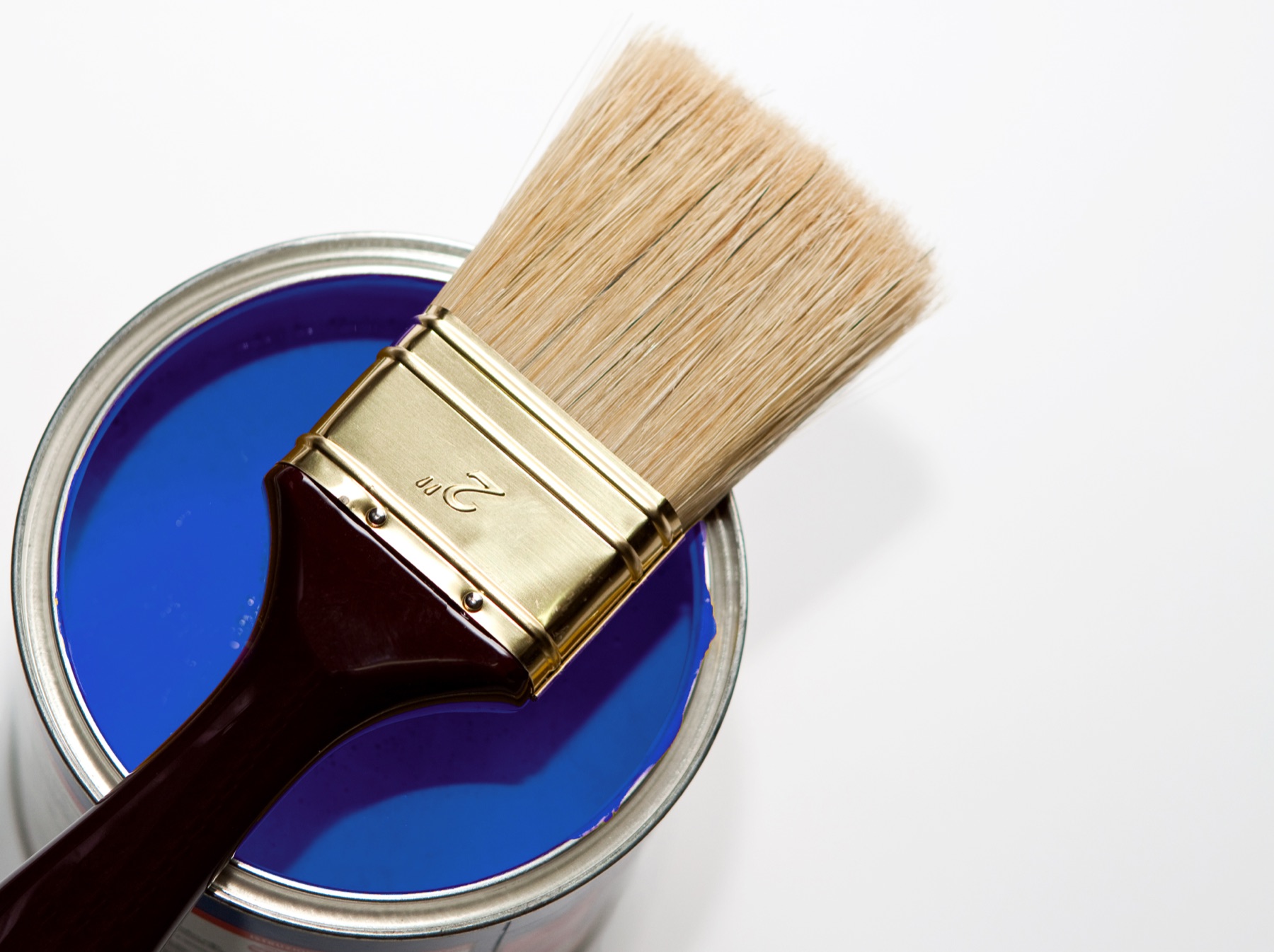 Tin of ultramarine blue paint with a brush laid across the opening