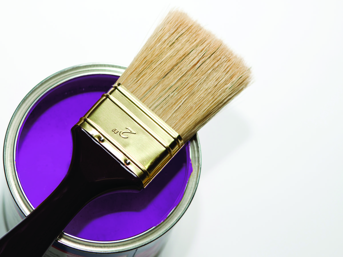Tin of ultramarine violet paint with a brush laid across the opening