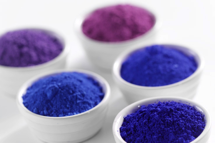 Bowls of ultramarine blue, violet and pink pigment powder